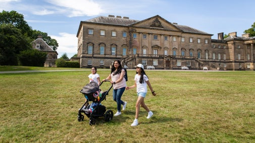 Visitors walking on the lawn in front of the mansion at Nostell, Yorkshire